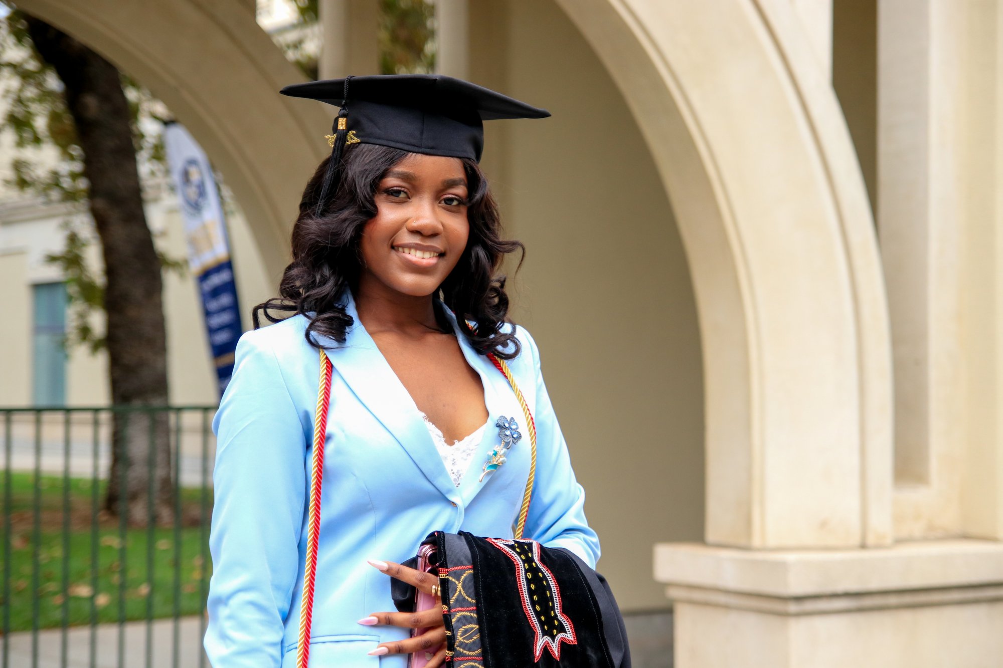 CalMU graduate in cap and gown at campus archway