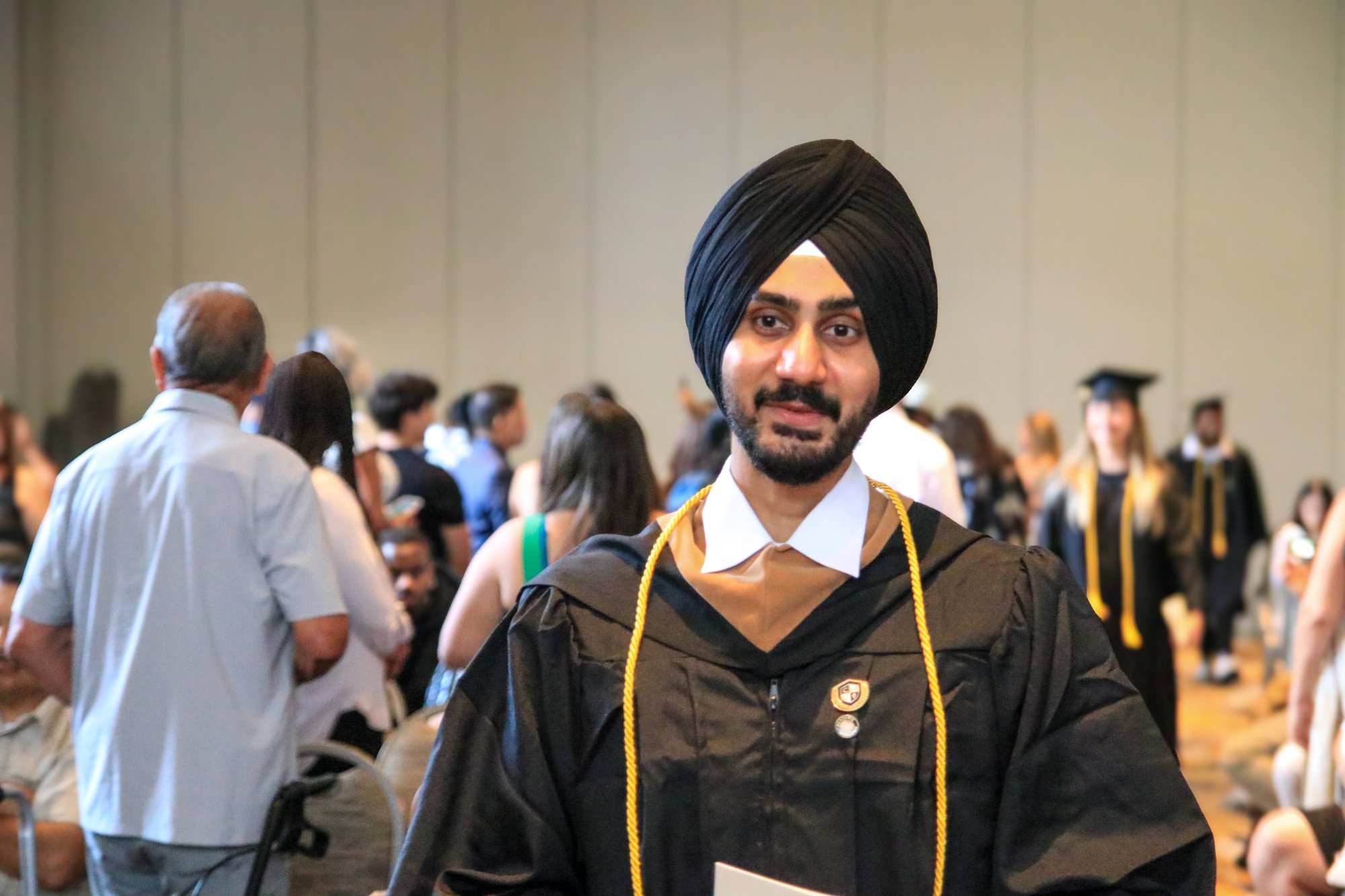 CalMU graduate holding diploma at commencement ceremo