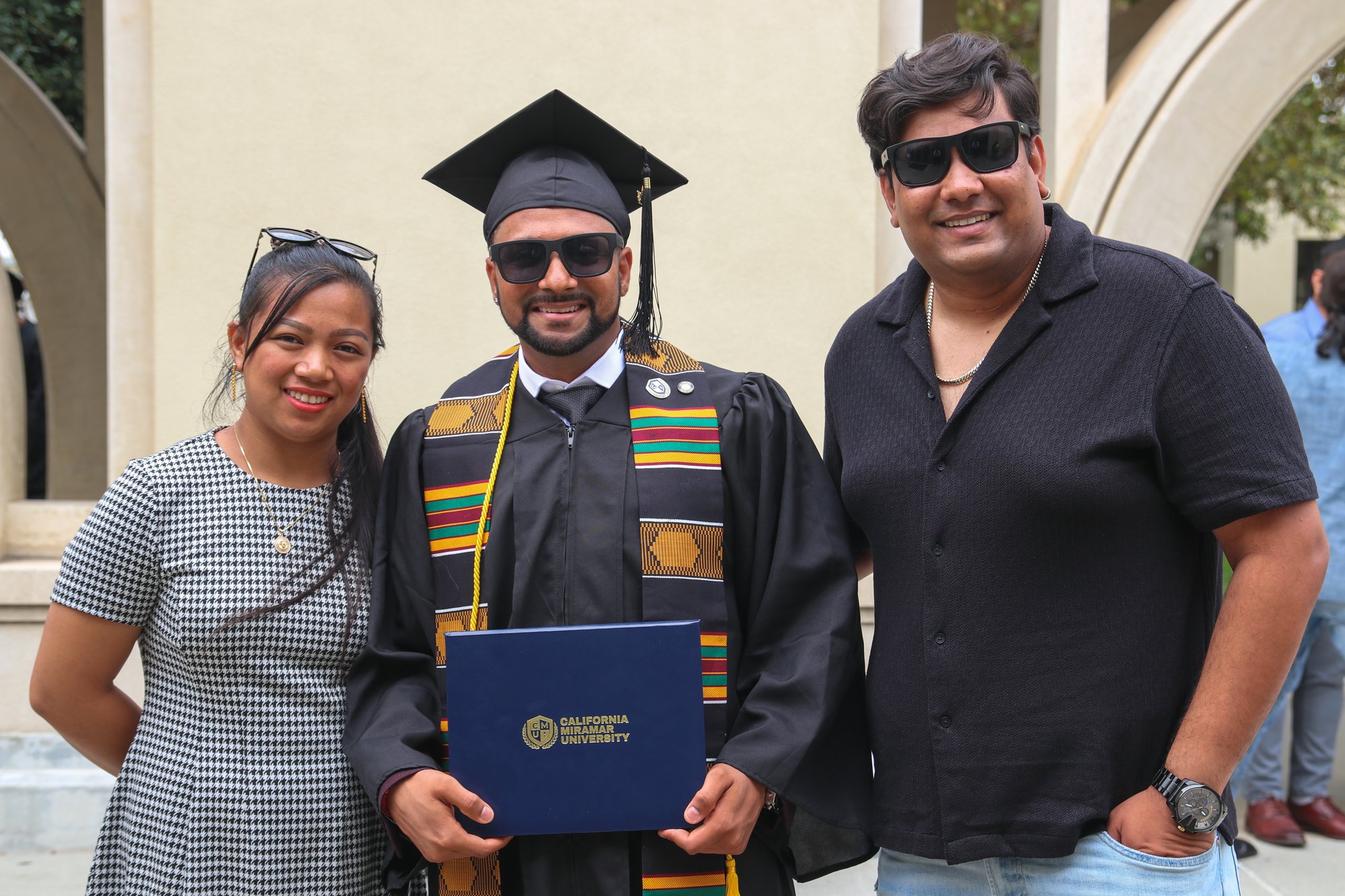 CalMU graduate celebrating with family and holding diploma