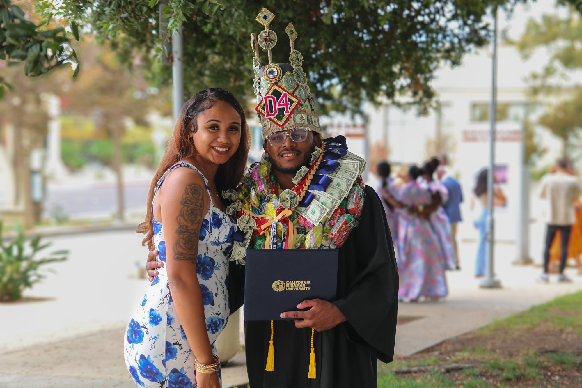 CalMU graduate with lei and flowers at commencement celebration